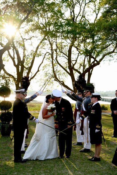 Bride and groom exchanging vows outdoors with wedding party.