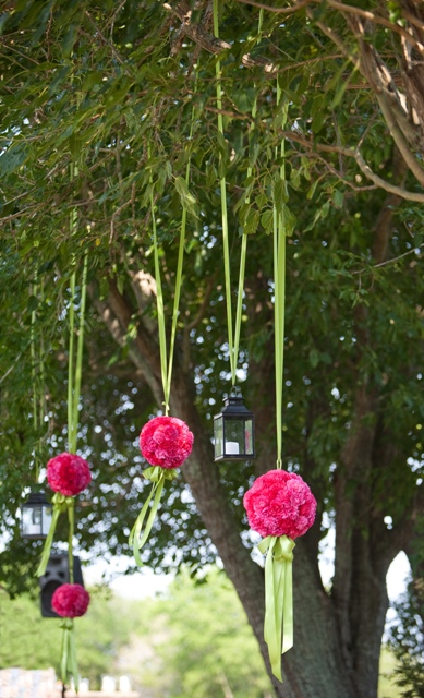 Decorative hanging lanterns and pink flowers from tree branches.