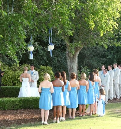 Outdoor wedding ceremony with bridal party standing.