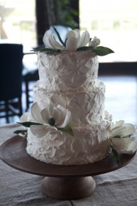 Two-tiered cake with white floral decorations.