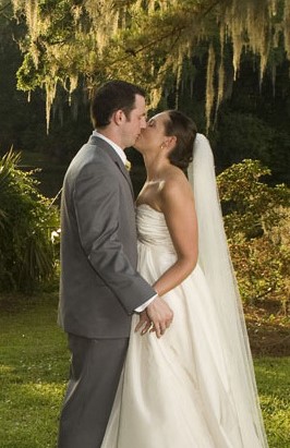 Bride and groom share a romantic kiss outdoors on their wedding day.