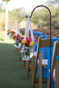 Outdoor wedding aisle with hanging flower arrangements.