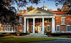 Historic mansion with grand columns and gardens.