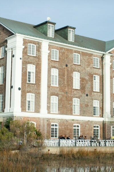 Brick building beside water with greenery.