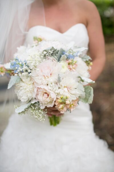 Bride holding bouquet of pastel flowers.