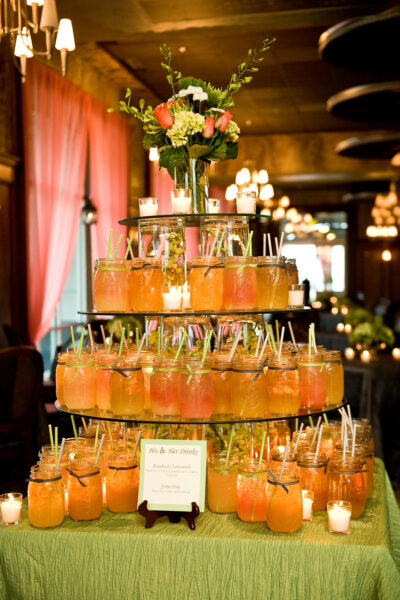 Elegant tiered display of orange drinks with floral centerpiece.