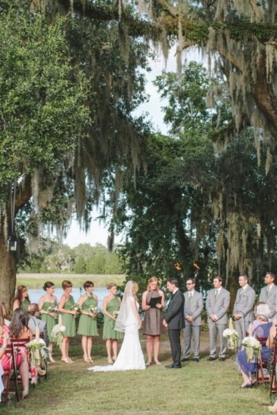 Outdoor wedding ceremony under large oak trees.