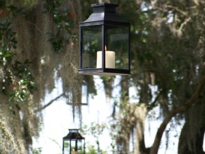 Hanging lanterns with candles in trees.