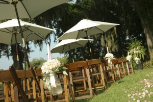 Outdoor wedding seating with umbrellas and flowers.