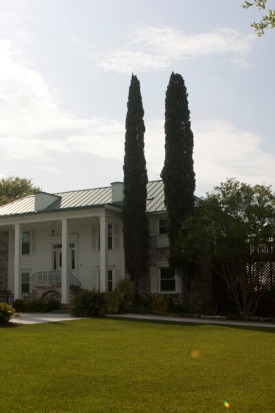 White house with trees and green lawn.