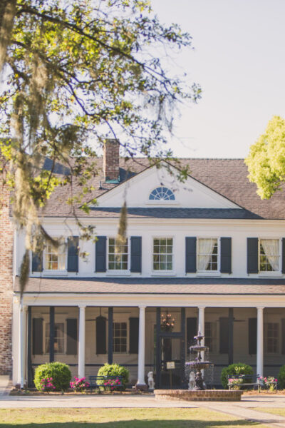 Colonial-style house with trees and fountain.