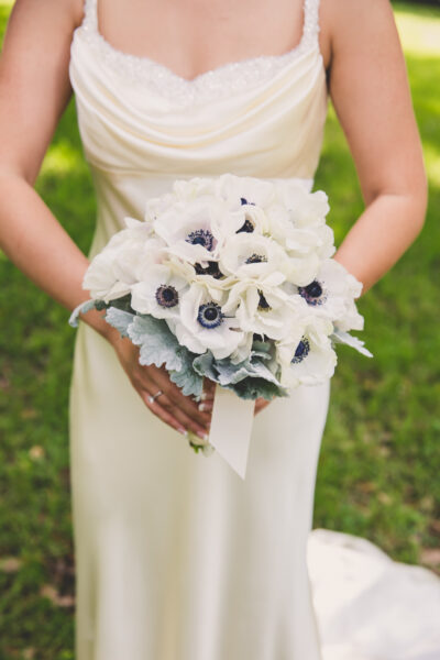 Bride holding a bouquet of white flowers with dark centers.