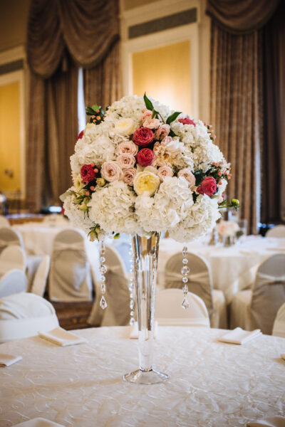 Elegant floral centerpiece with white and pink flowers on a tall glass vase.