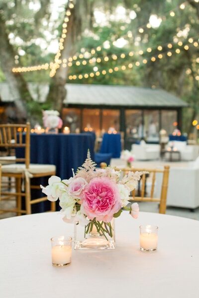 Elegant wedding table centerpiece with pink and white flowers and candles.