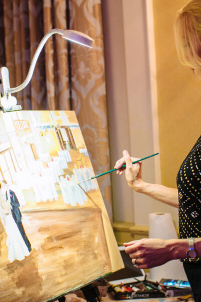 Artist painting a wedding scene on canvas.