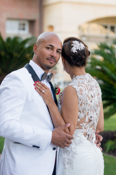 Bride and groom embracing outdoors, wedding attire.