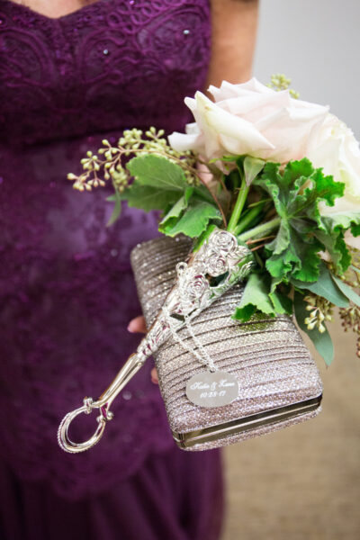 Elegant silver keychain with a crystal heart near a bouquet of white roses.