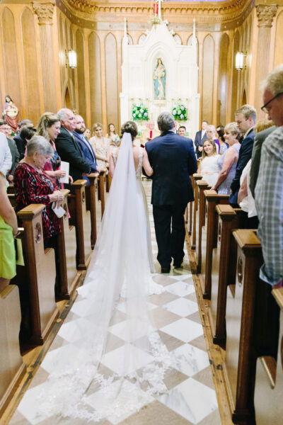 Bride walking down the aisle with her escort in a church ceremony.