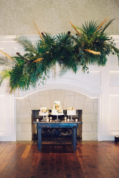 Festive greenery and gold accents decorate a white fireplace mantel.