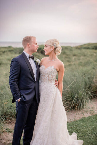Bride and groom embracing outdoors in wedding attire.