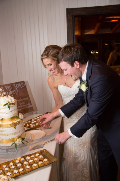 Bride and groom cutting their wedding cake together indoors.