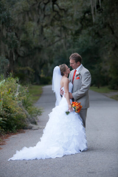 Bride and groom sharing a kiss on a path surrounded by greenery.