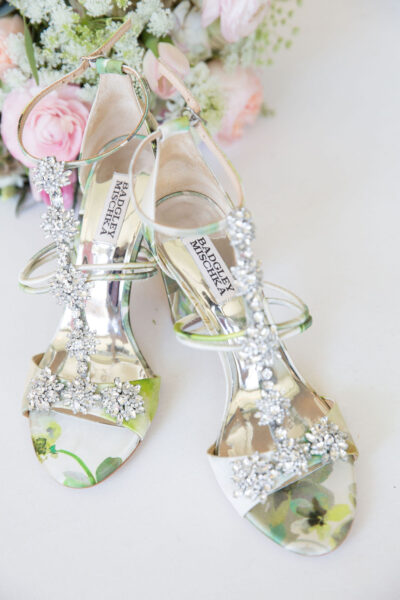 Elegant silver high-heeled sandals with floral details and rhinestones.