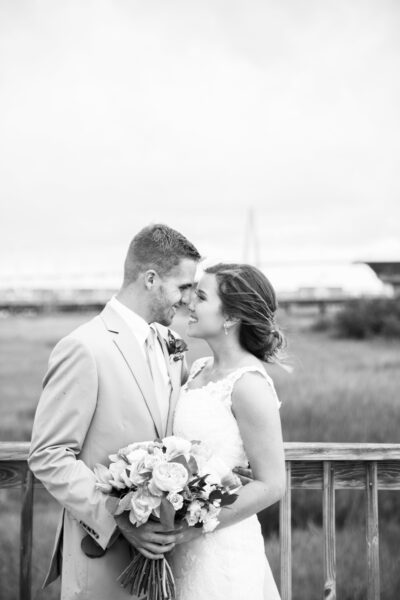 Black and white photo of a couple sharing a tender moment, likely at their wedding.