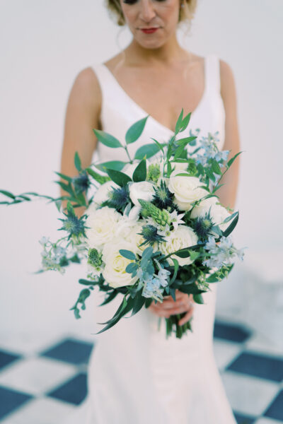 Bride holding elegant white and green floral bouquet.