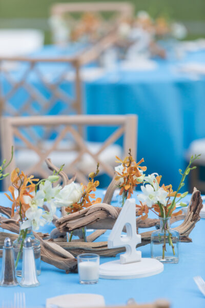 Elegant table centerpiece with flowers and driftwood at event.