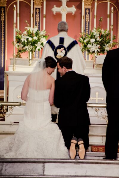 Bride and groom kneeling at altar during wedding ceremony.