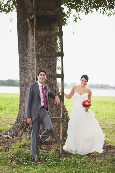 Bride and groom outdoors by a large tree, celebrating their wedding day.