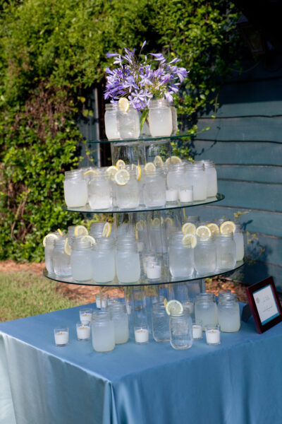 A tiered display of ice glasses with lemon slices outdoors.
