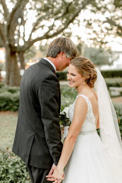 A joyful bride and groom share a tender moment outdoors.