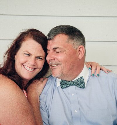 Bride holding a bouquet of white flowers with lace gloves.