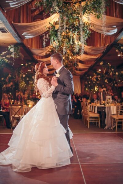 Bride and groom share their first dance at a warmly decorated wedding reception.