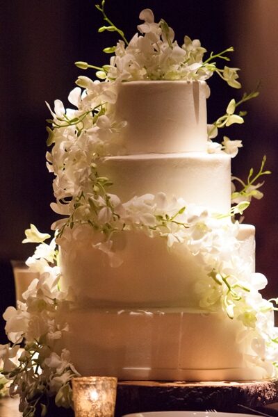 Elegant white tiered wedding cake adorned with cascading white flowers.
