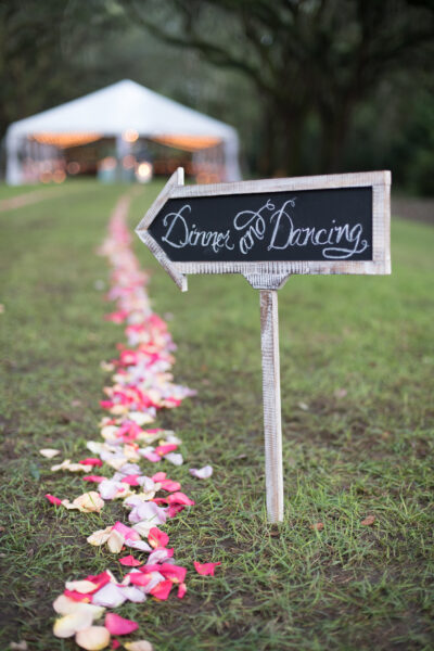 A wooden sign points to the dance area along a petal-strewn path.