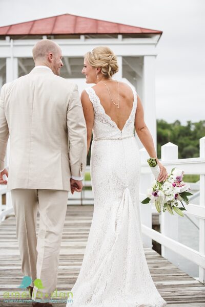 Bride and groom walking hand in hand outdoors.