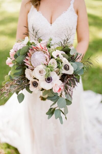 Bride holding a lush bouquet of white and pink flowers with greenery.