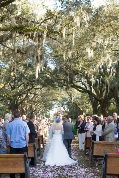 Outdoor wedding ceremony under large oak trees with hanging Spanish moss.