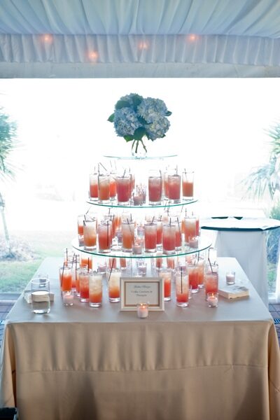A tiered display of cocktails garnished with flowers at an event.