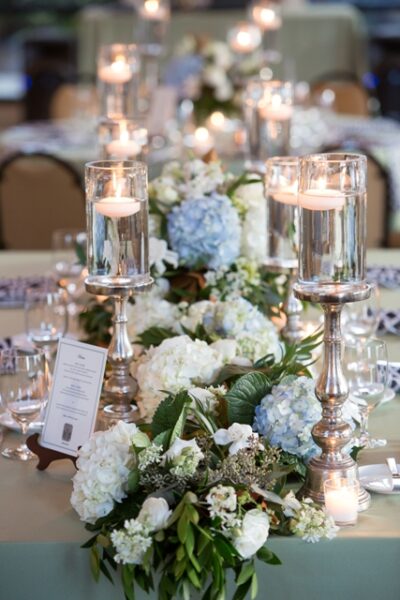 Elegant wedding table centerpiece with candles and blue hydrangeas.