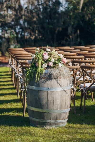 Rustic wedding barrel decorated with flowers and greenery.