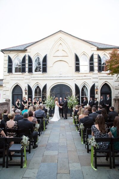 Bride and groom stand before guests outside historic church for wedding ceremony.
