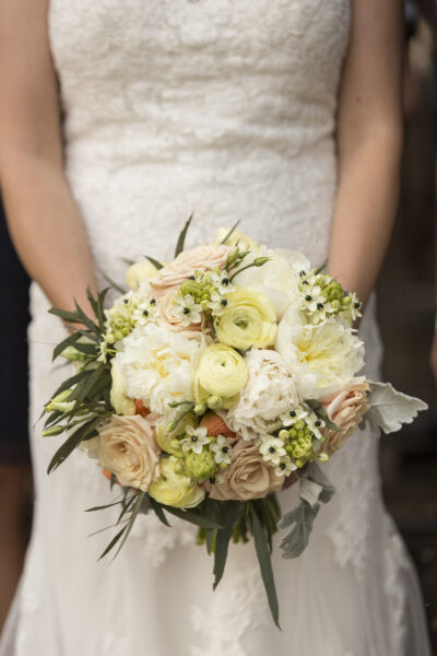 Bride holding a delicate bouquet of white and cream flowers.