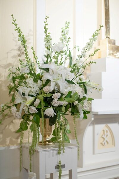 Elegant white floral arrangement with lilies and greenery in a glass vase.