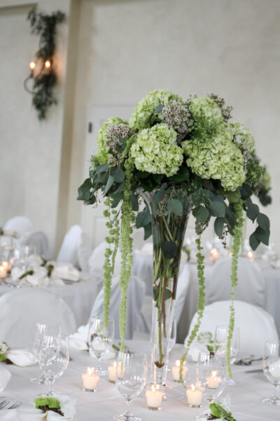 Elegant green and white floral centerpiece in a tall vase.
