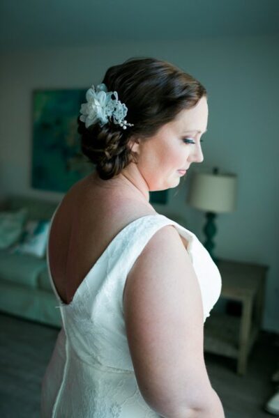 Bride in a white dress with side-swept hair and floral hairpiece.
