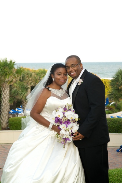 Bride in elegant white dress holding bouquet outdoors.